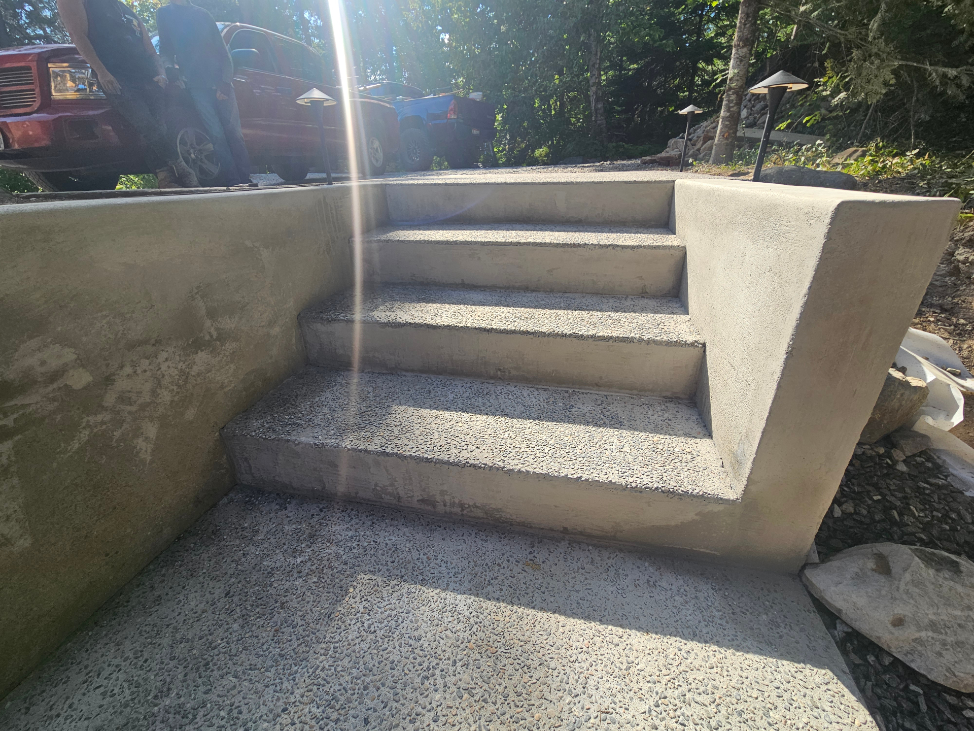 Finished broom-textured concrete stairs with sun flare and forest backdrop